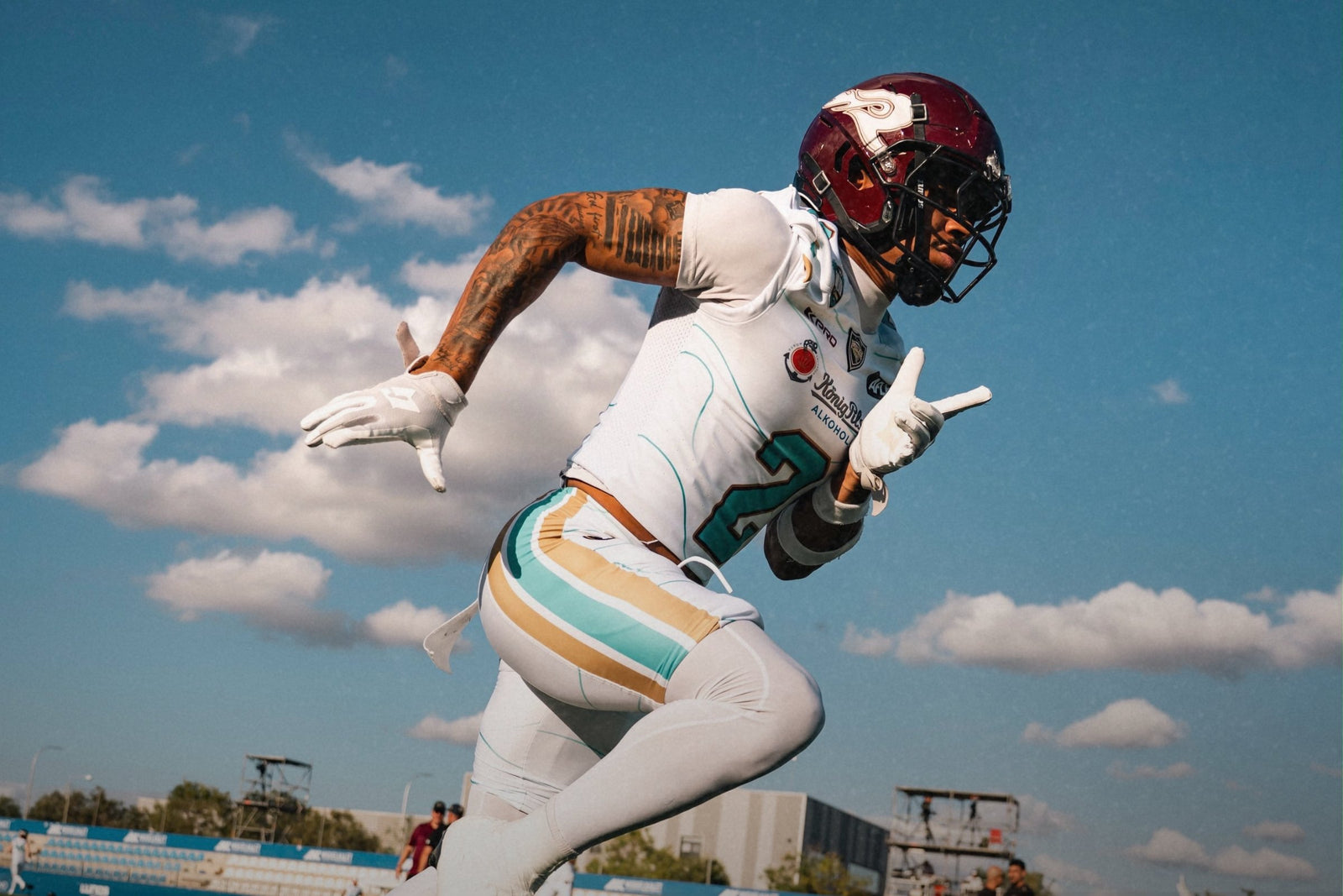 Receptor de football americano corriendo a contrapicado contra el cielo, con guantes GRINDIN